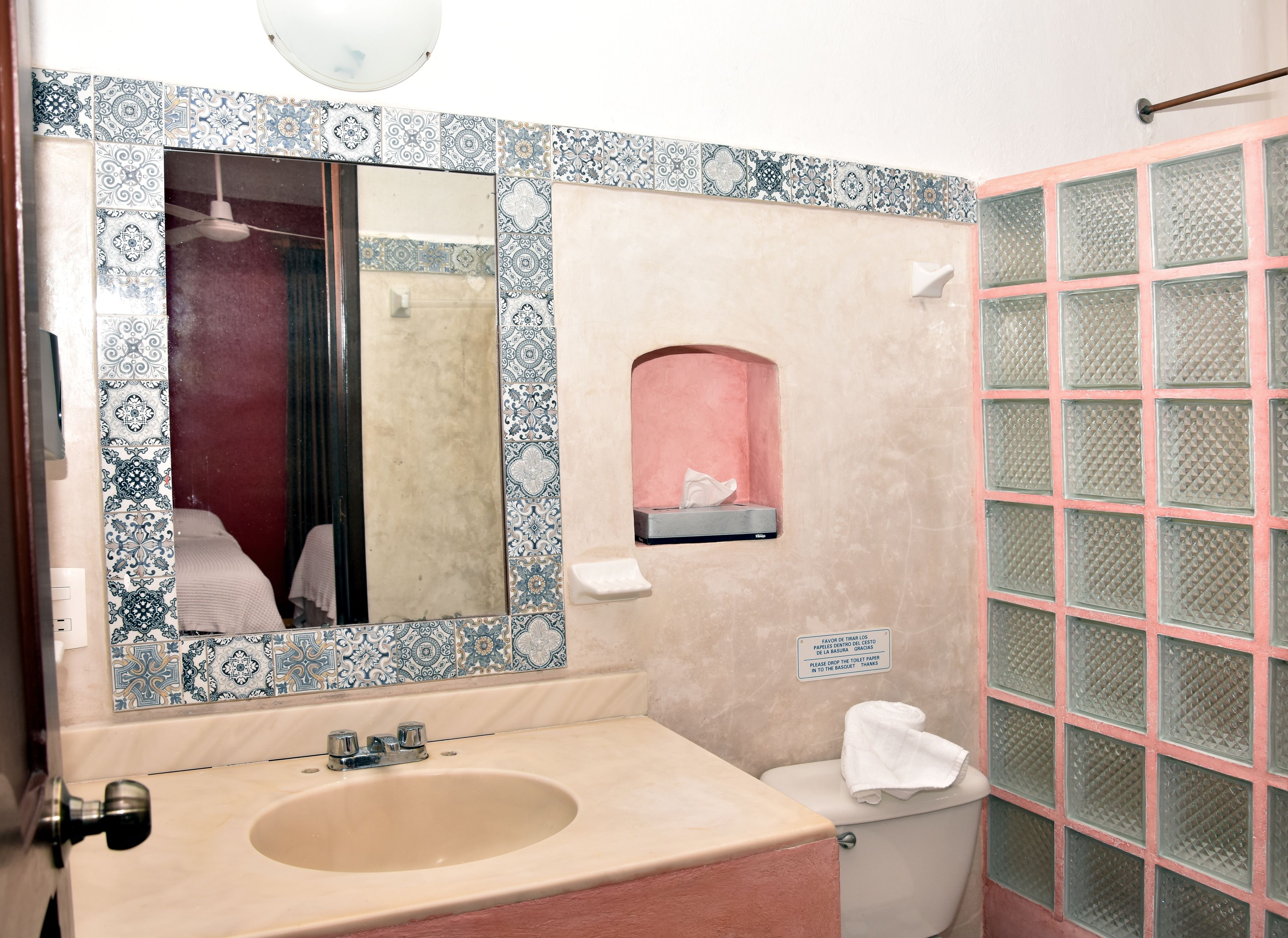 Une salle de bain équipée d’un lavabo, d’un miroir, de toilettes et d’une paroi en verre.