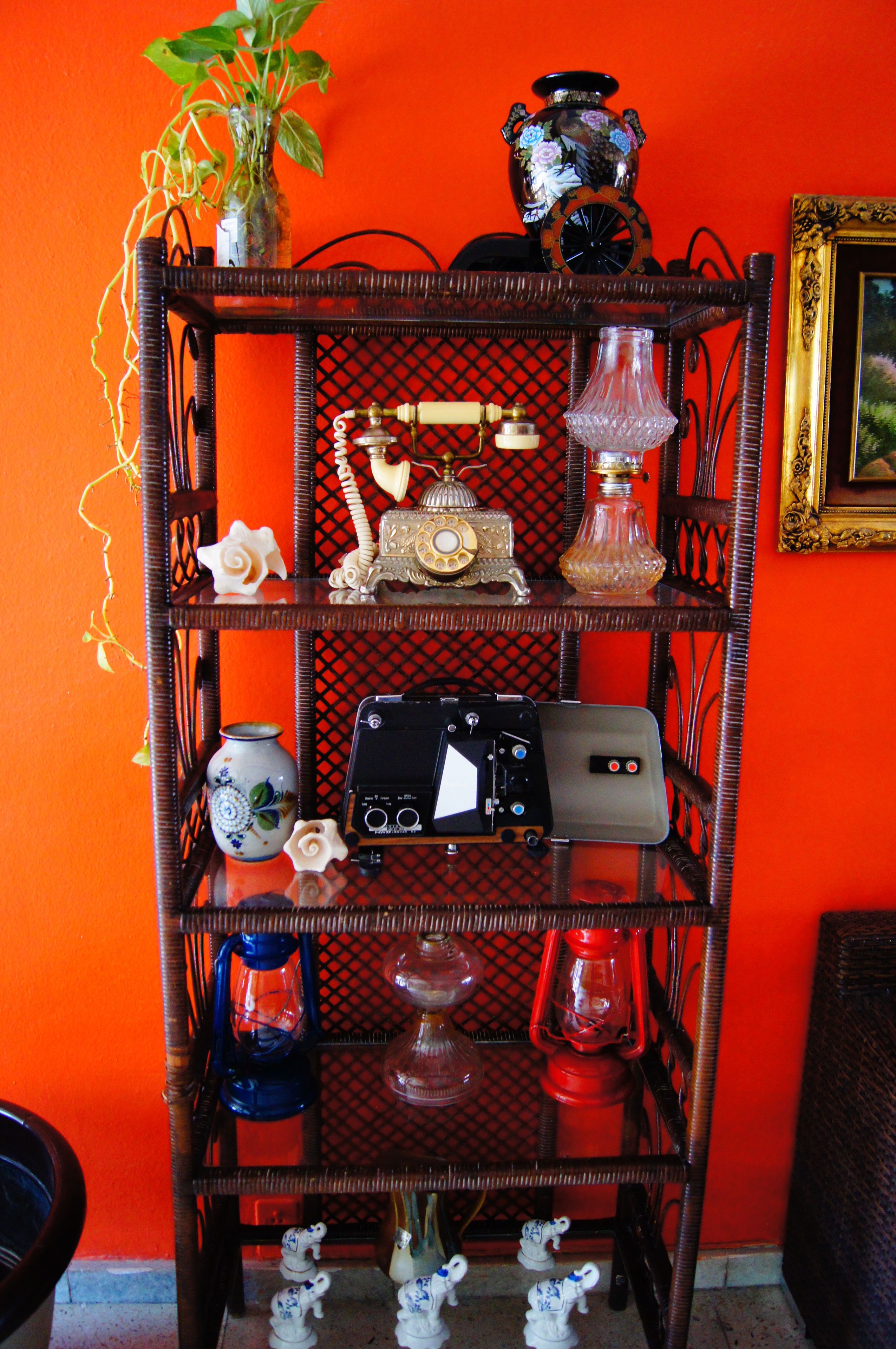 Een meerlaagse houten plank met diverse decoratieve objecten, waaronder een vintage radio, een vaas en beeldjes.