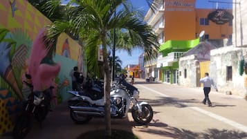 A street with colorful buildings, a mural, and parked motorcycles.