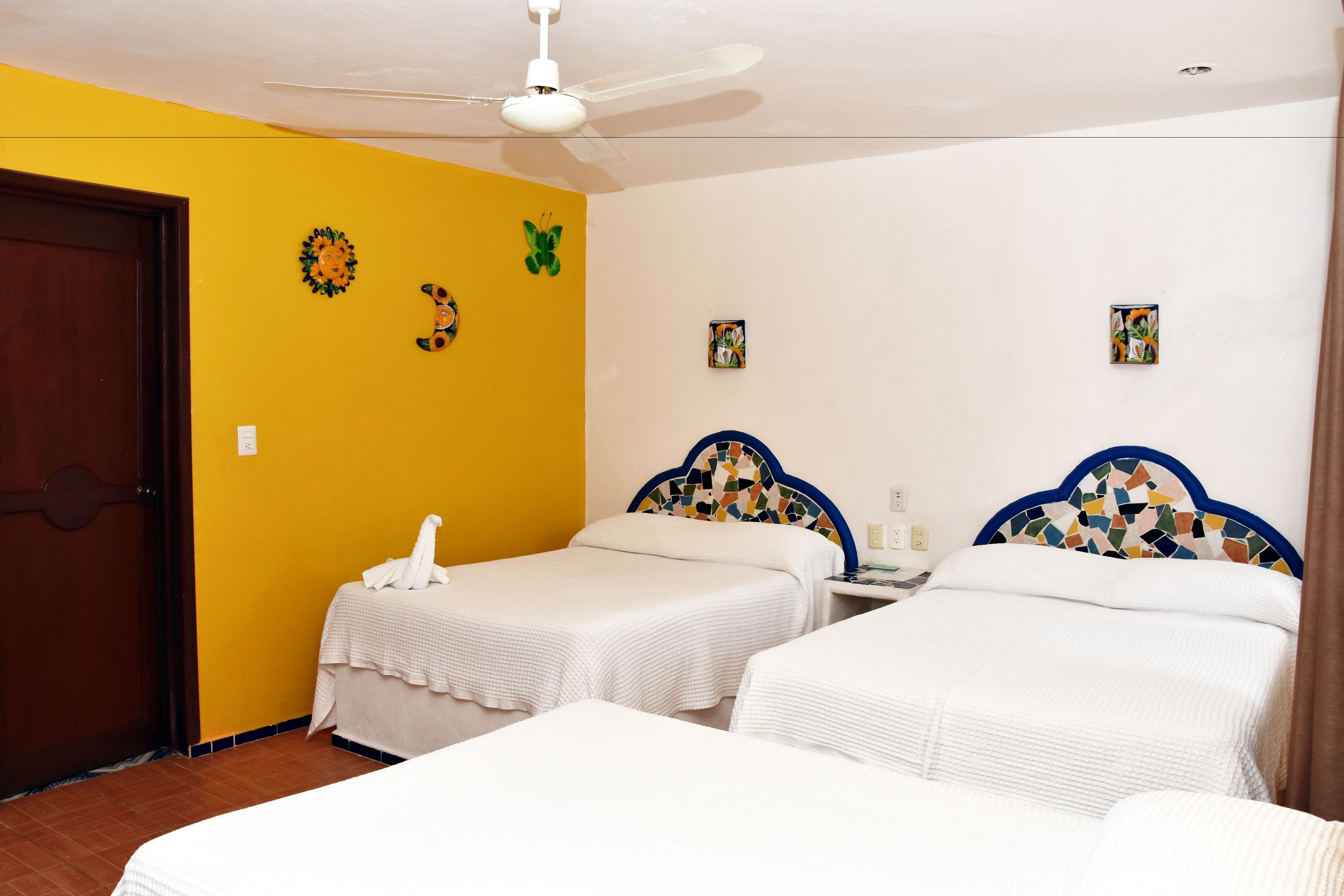 A hotel room with two beds, a ceiling fan, and decorative wall art.