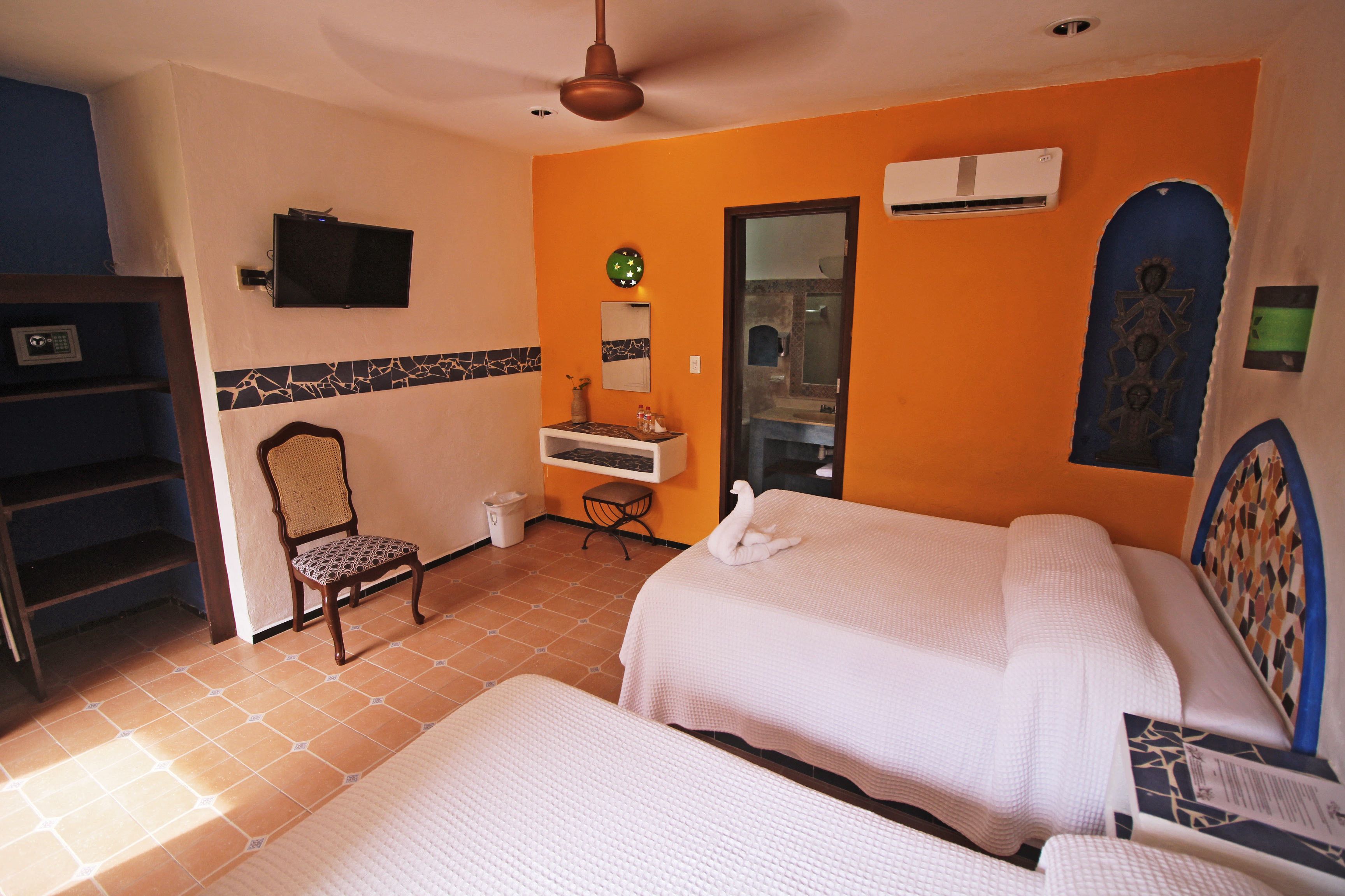 A hotel room with two beds, a television, a clock, a mirror, and a bathroom door.