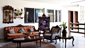 Sala de estar com sofá marrom, almofadas estampadas, mesa de centro e lustre.