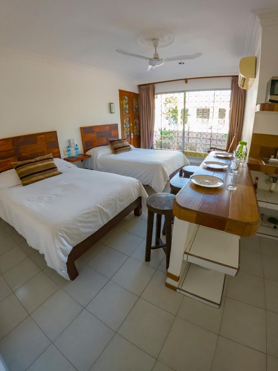 Una habitación de hotel con dos camas, una mesa de comedor y un balcón con vistas.