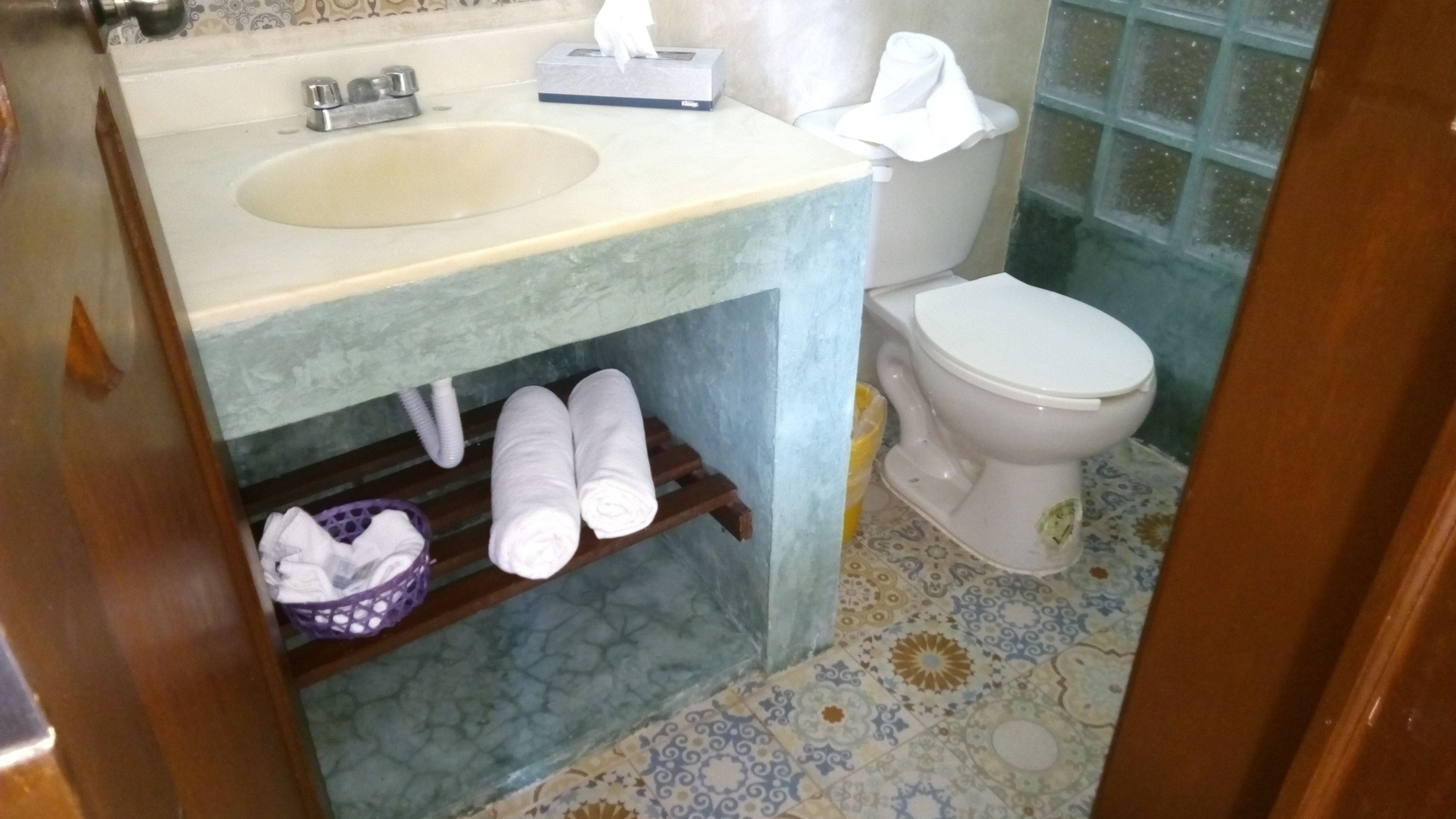 A bathroom with a sink, toilet, and a shelf with towels.