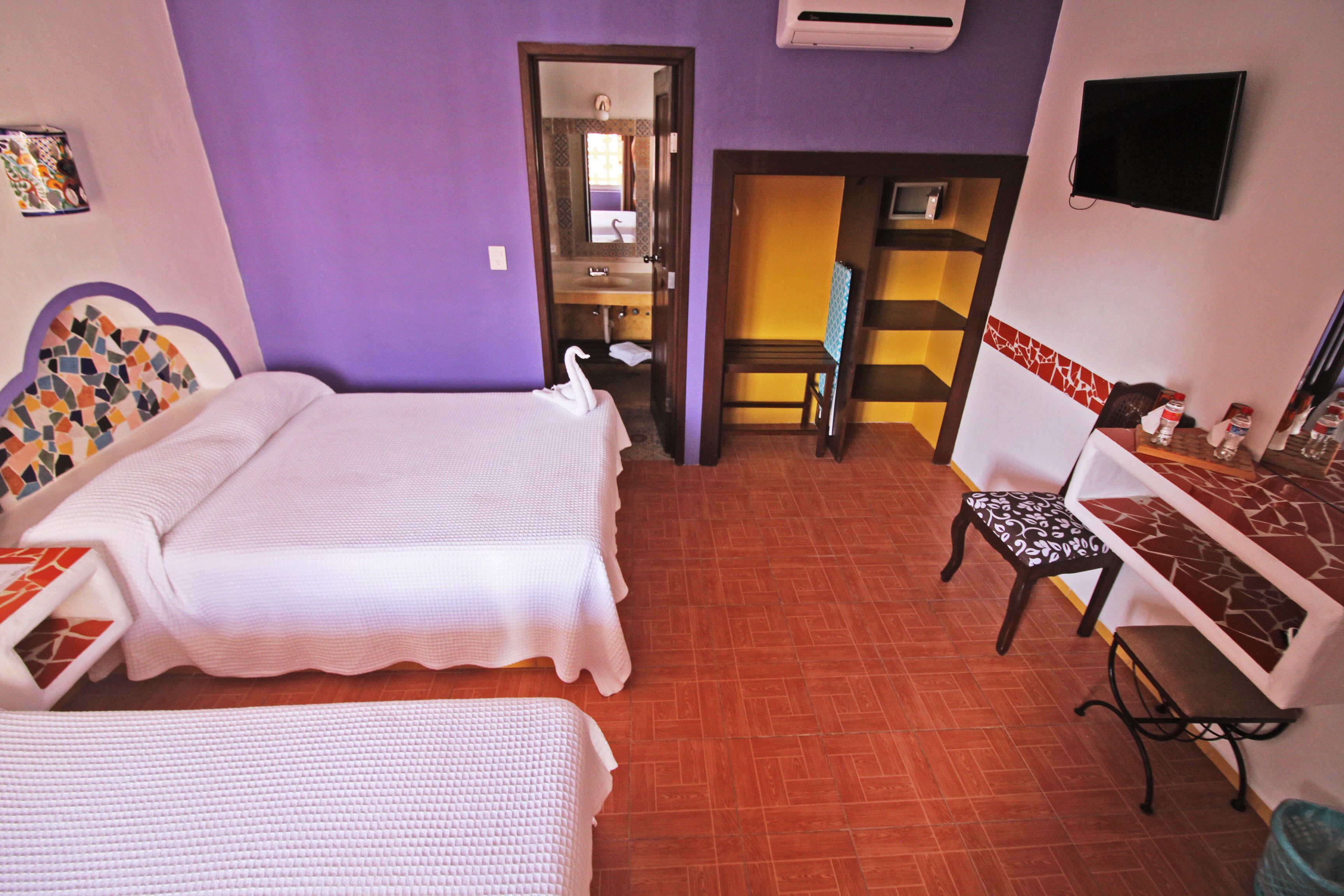 A hotel room with two beds, a desk, a chair, and a TV.