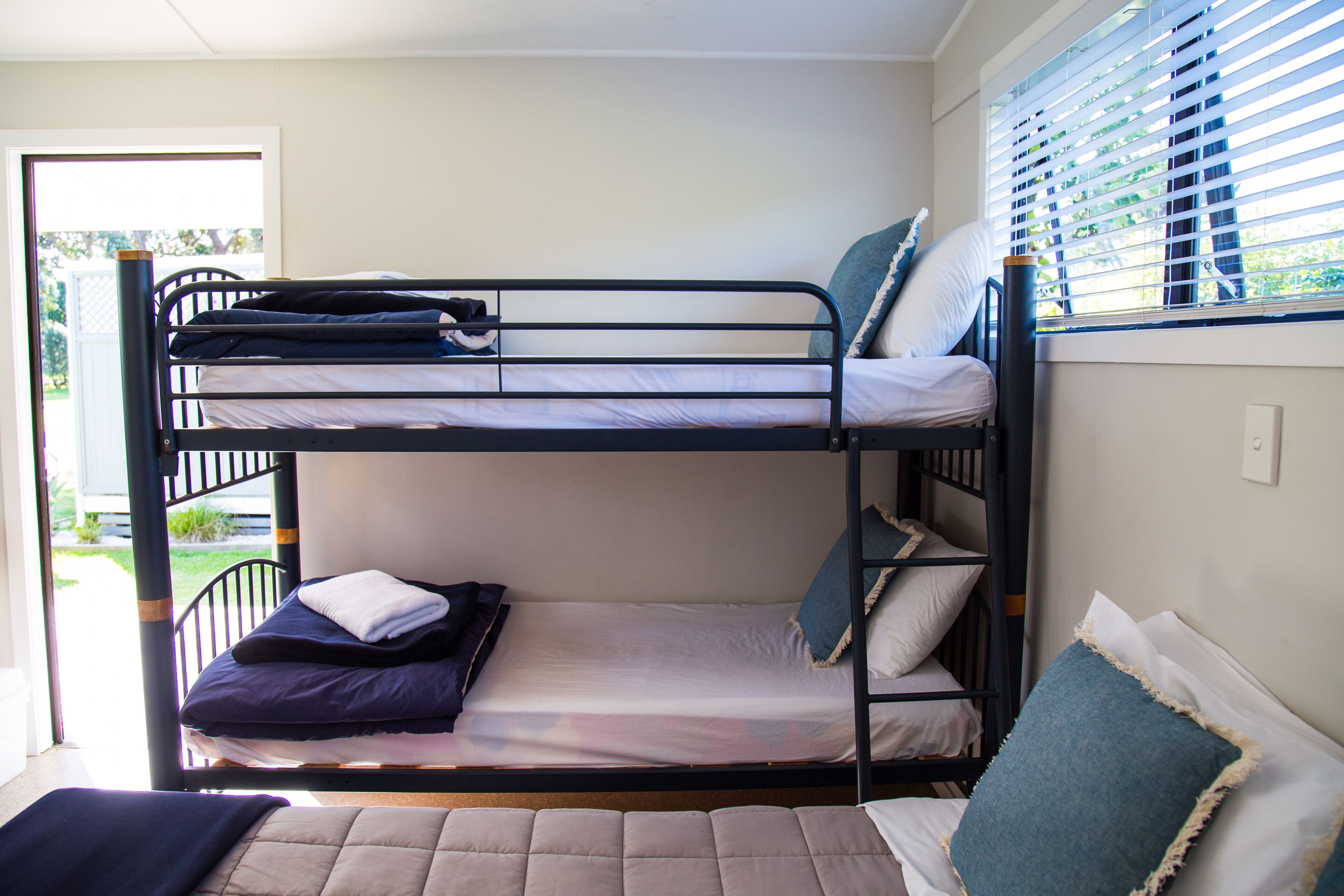 Een slaapkamer met stapelbed, een raam en een deur.