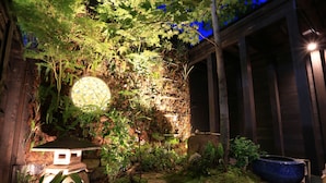 Um jardim com estrutura de madeira, um elemento de água e diversas plantas.