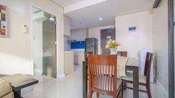 Una cocina moderna con refrigerador, estufa y armarios. Hay un comedor con una mesa y sillas.