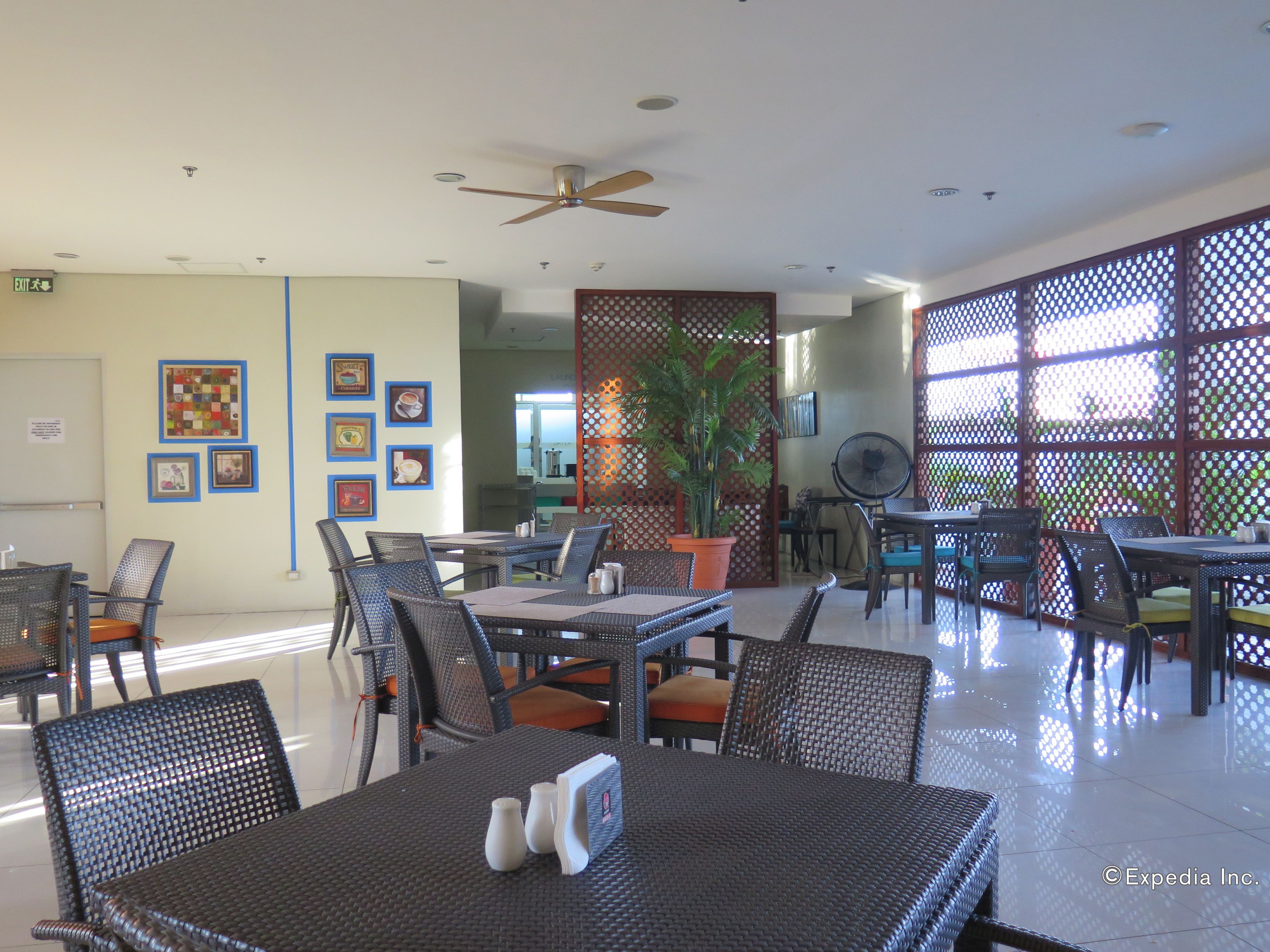 A spacious indoor dining area with multiple tables and chairs, ceiling fans, and a decorative plant.