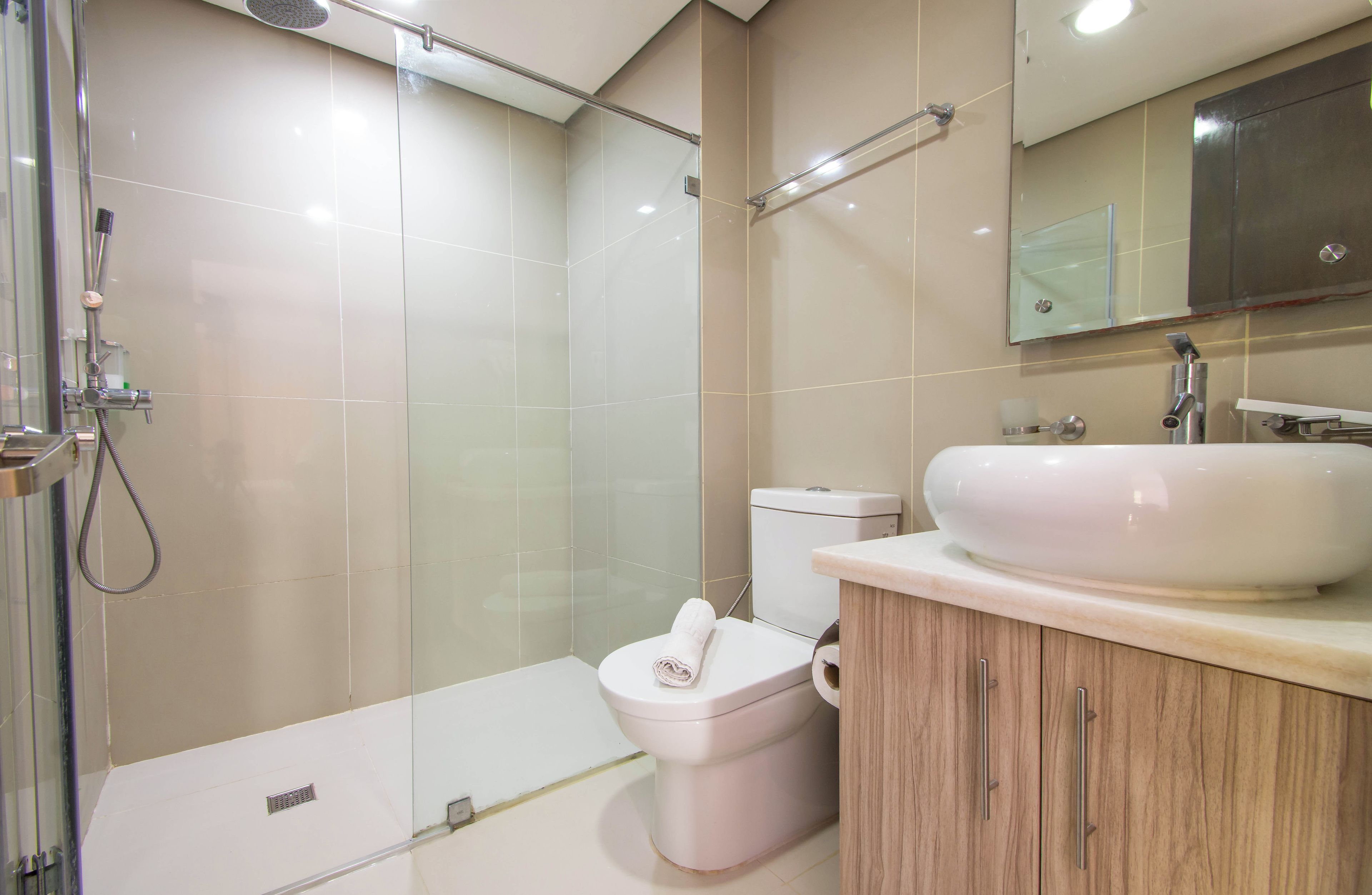 Un baño moderno con cabina de ducha de vidrio, inodoro y tocador con lavamanos.