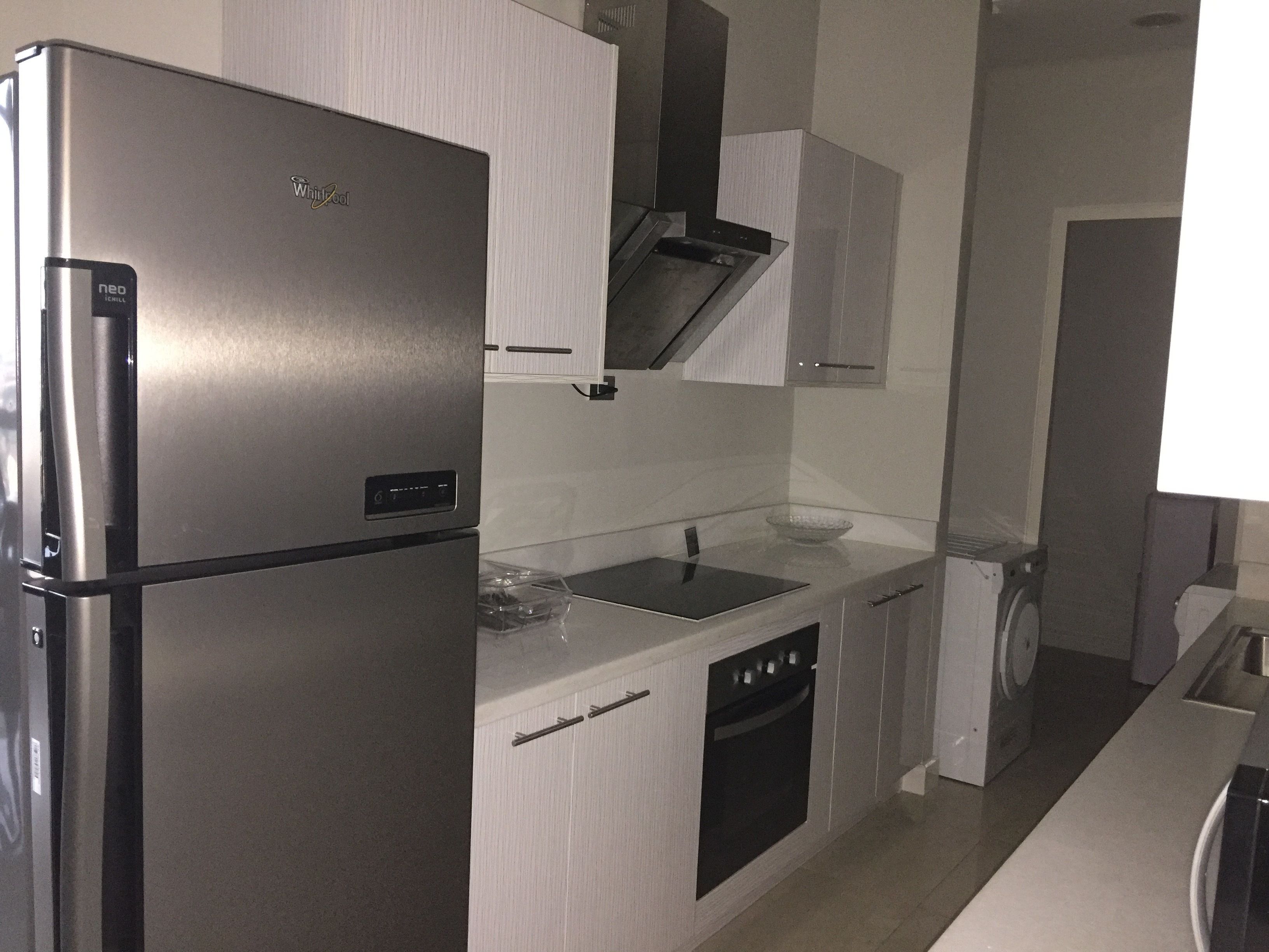 A modern kitchen with a stainless steel refrigerator, a built-in oven, and a dishwasher.