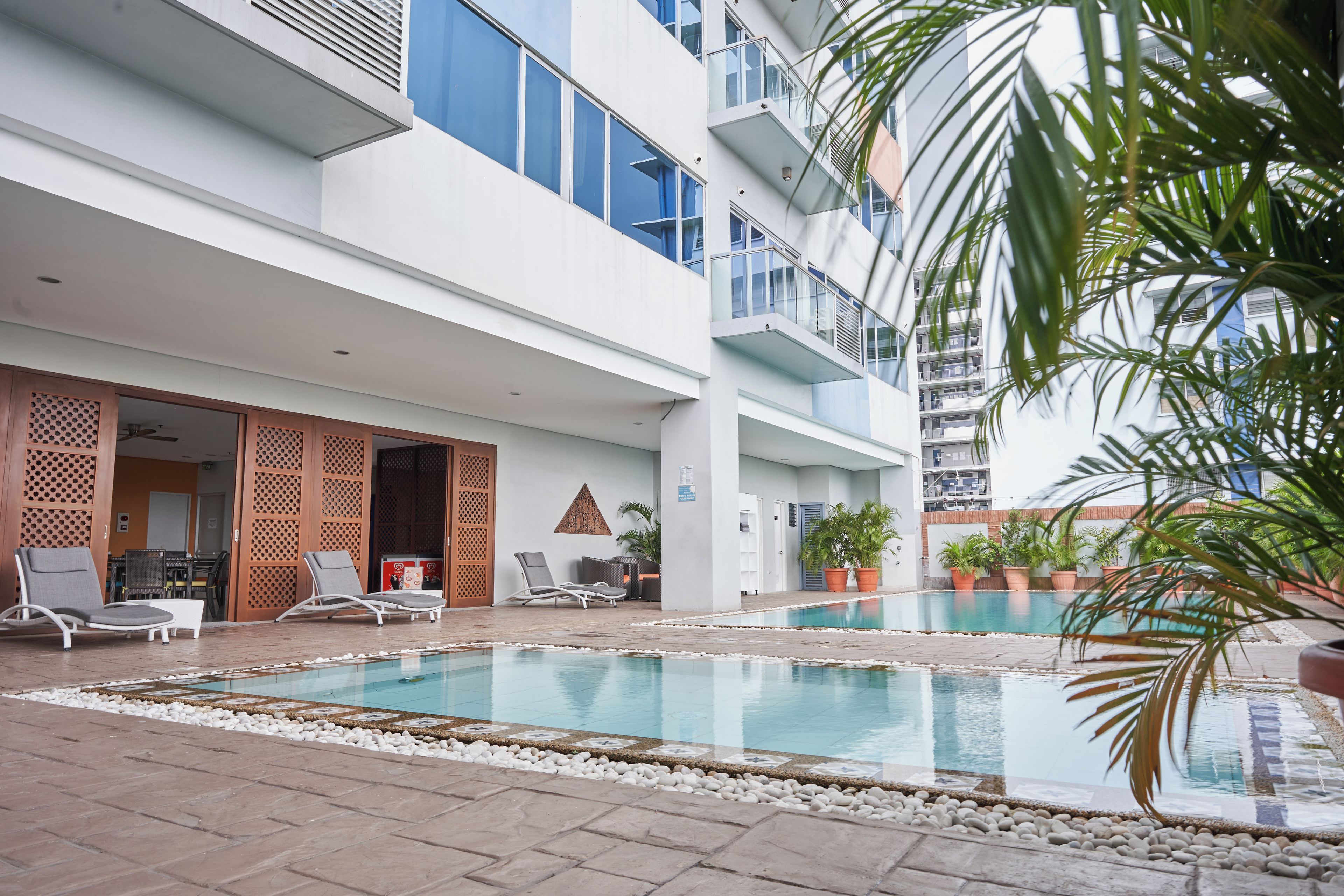 A pool area with lounge chairs and a building with multiple floors and balconies.