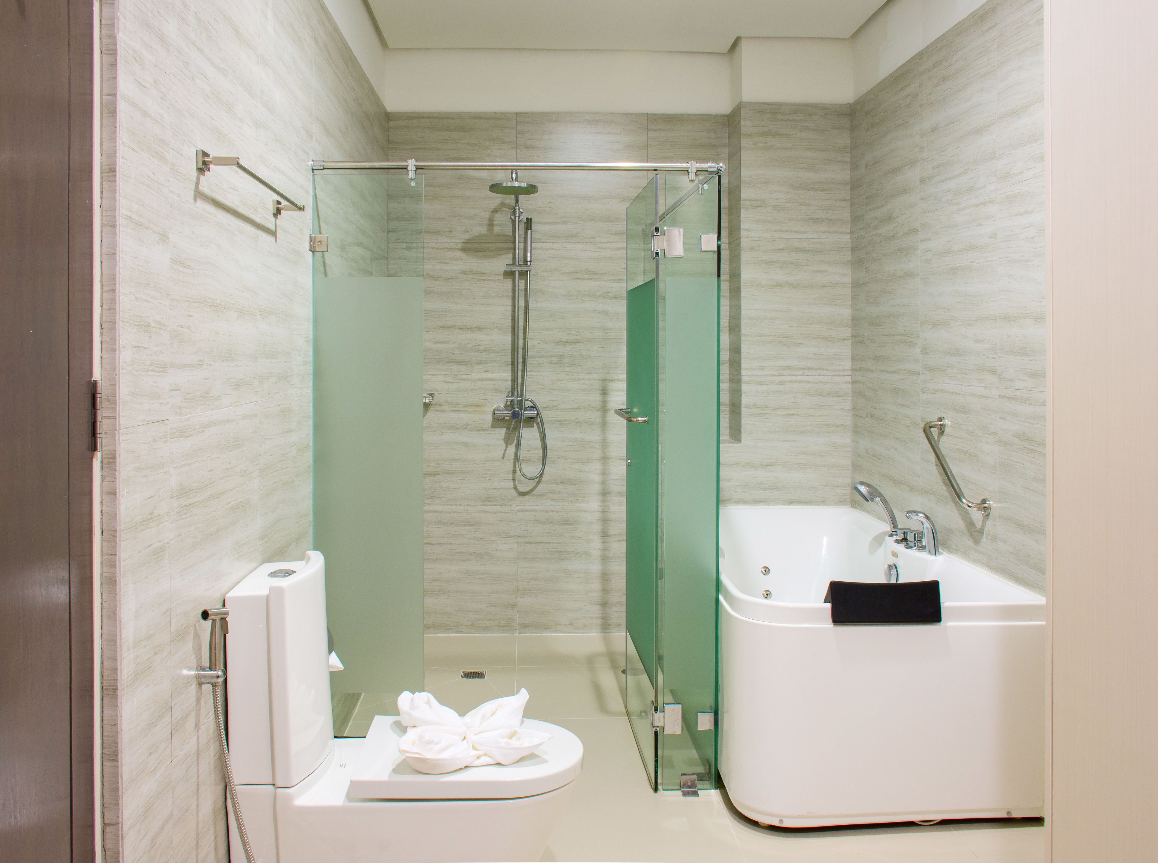 A modern bathroom with a glass-enclosed shower, a white toilet, and a white bathtub.