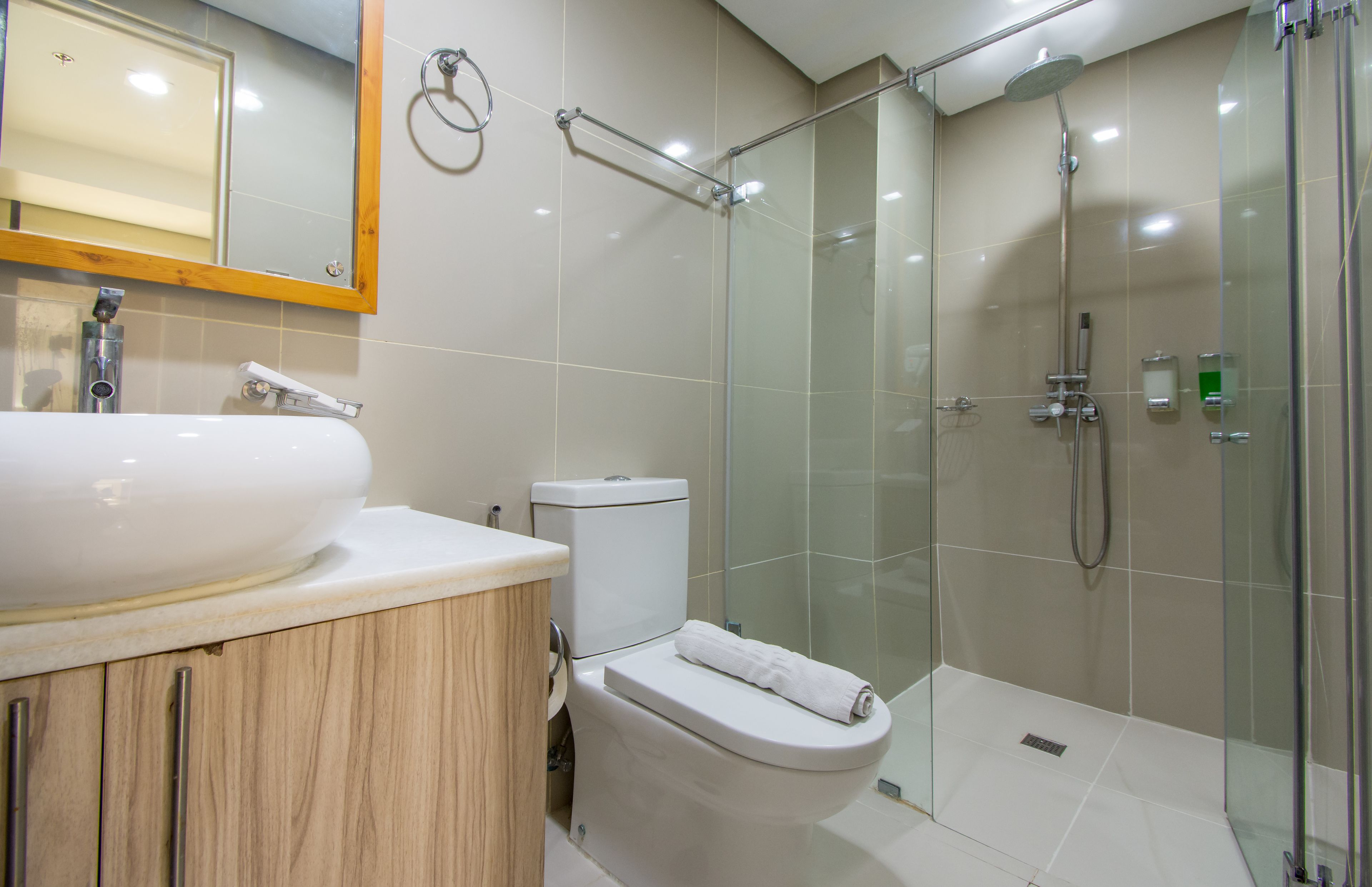 A modern bathroom with a large white sink, a toilet, and a glass-enclosed shower area.