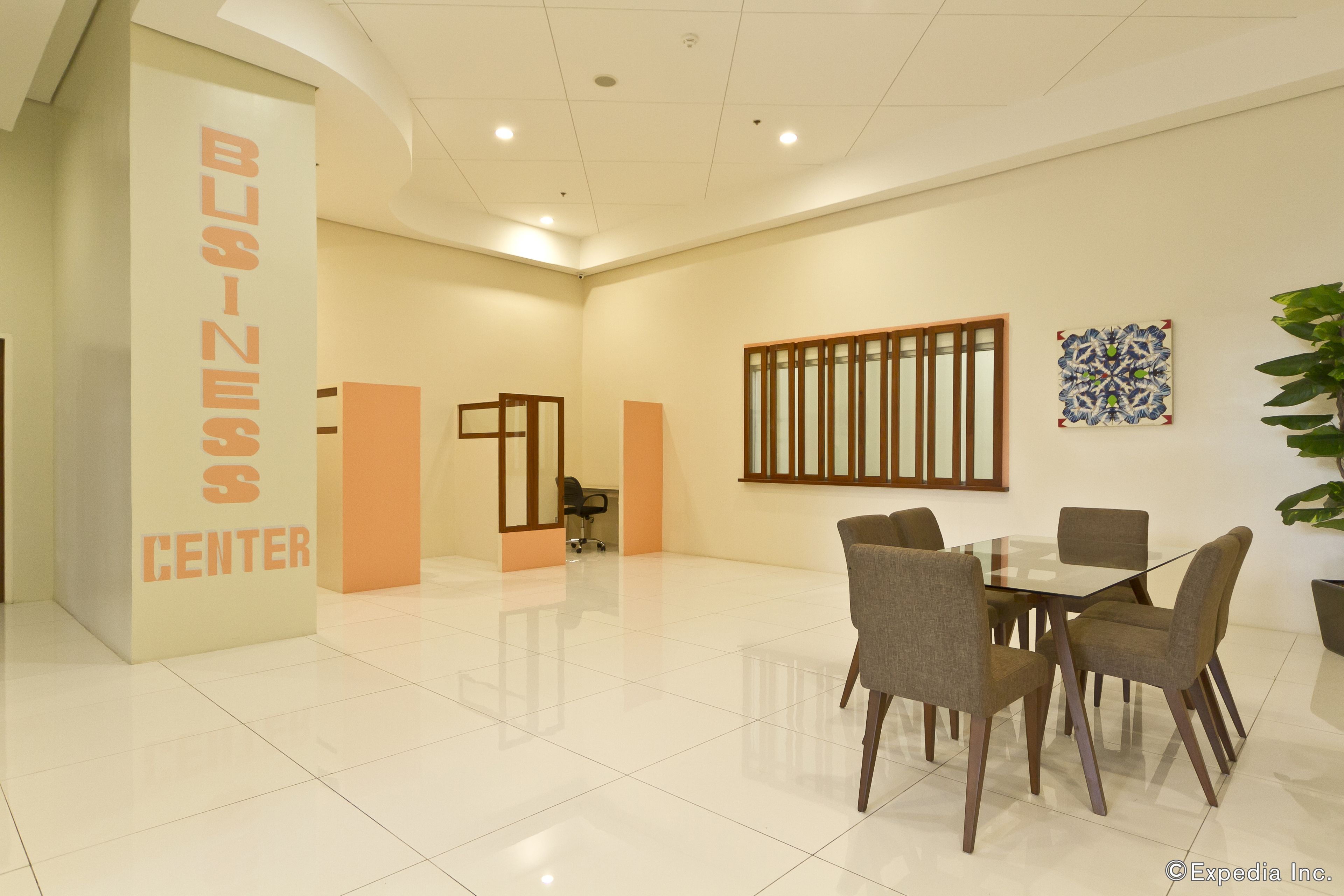A spacious business center with a large table and chairs, a reception desk, and a decorative wall piece.