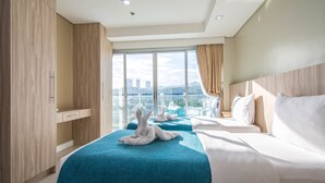 A hotel room with two beds, a large window with a city view, and a wardrobe. - Alicia Apartelle (Cebu City)