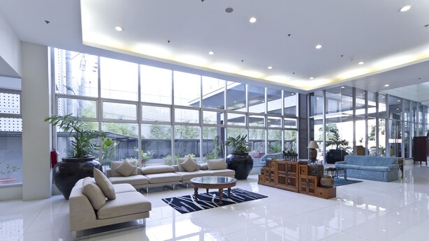 A spacious lobby with a large sofa, a coffee table, and potted plants. - Alicia Apartelle (Cebu City)