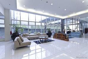 A spacious lobby with a large sofa, a coffee table, and potted plants.