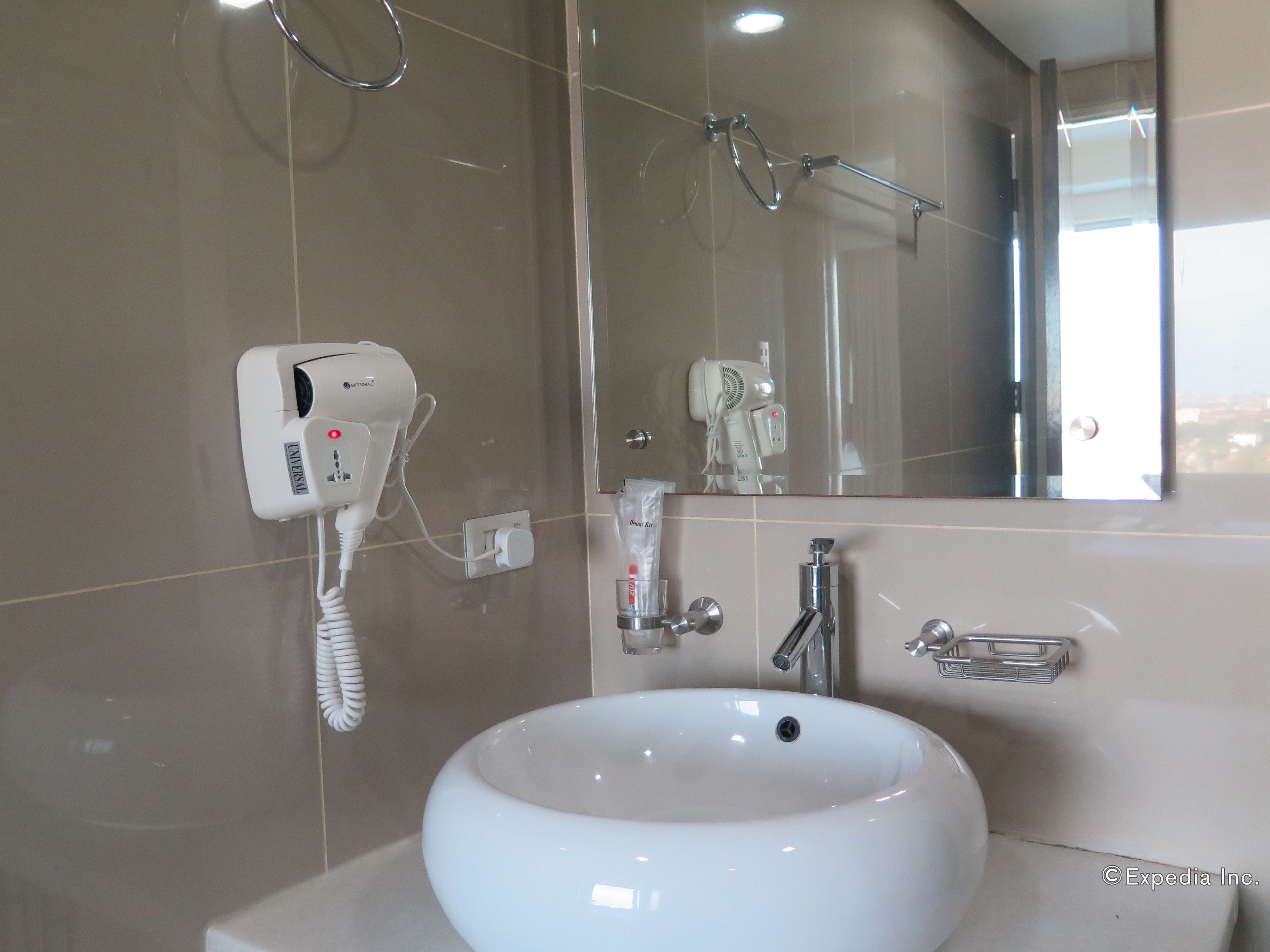 Un bagno con lavandino bianco, asciugacapelli e specchio.