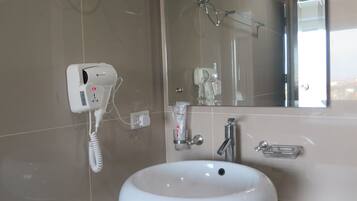 Un bagno con lavandino bianco, asciugacapelli e specchio.