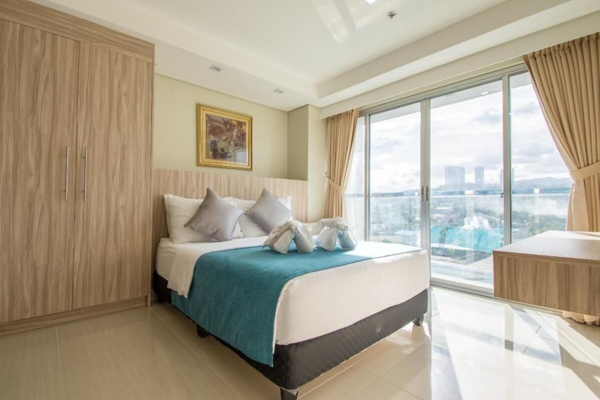 Una habitación de hotel con una cama grande, vistas a la ciudad y un armario de madera.