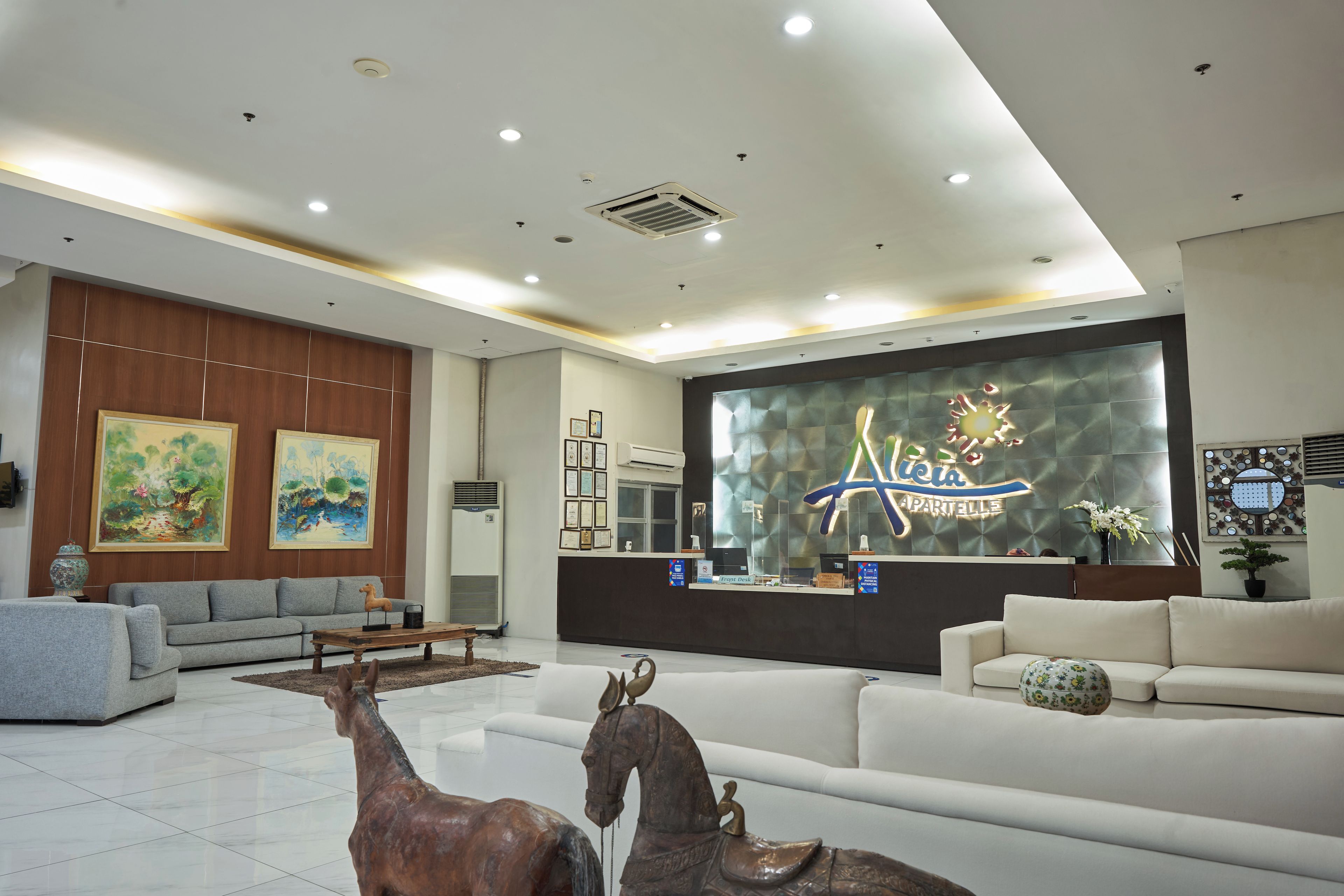 A modern reception area with a reception desk, seating arrangements, and decorative elements like paintings and sculptures.