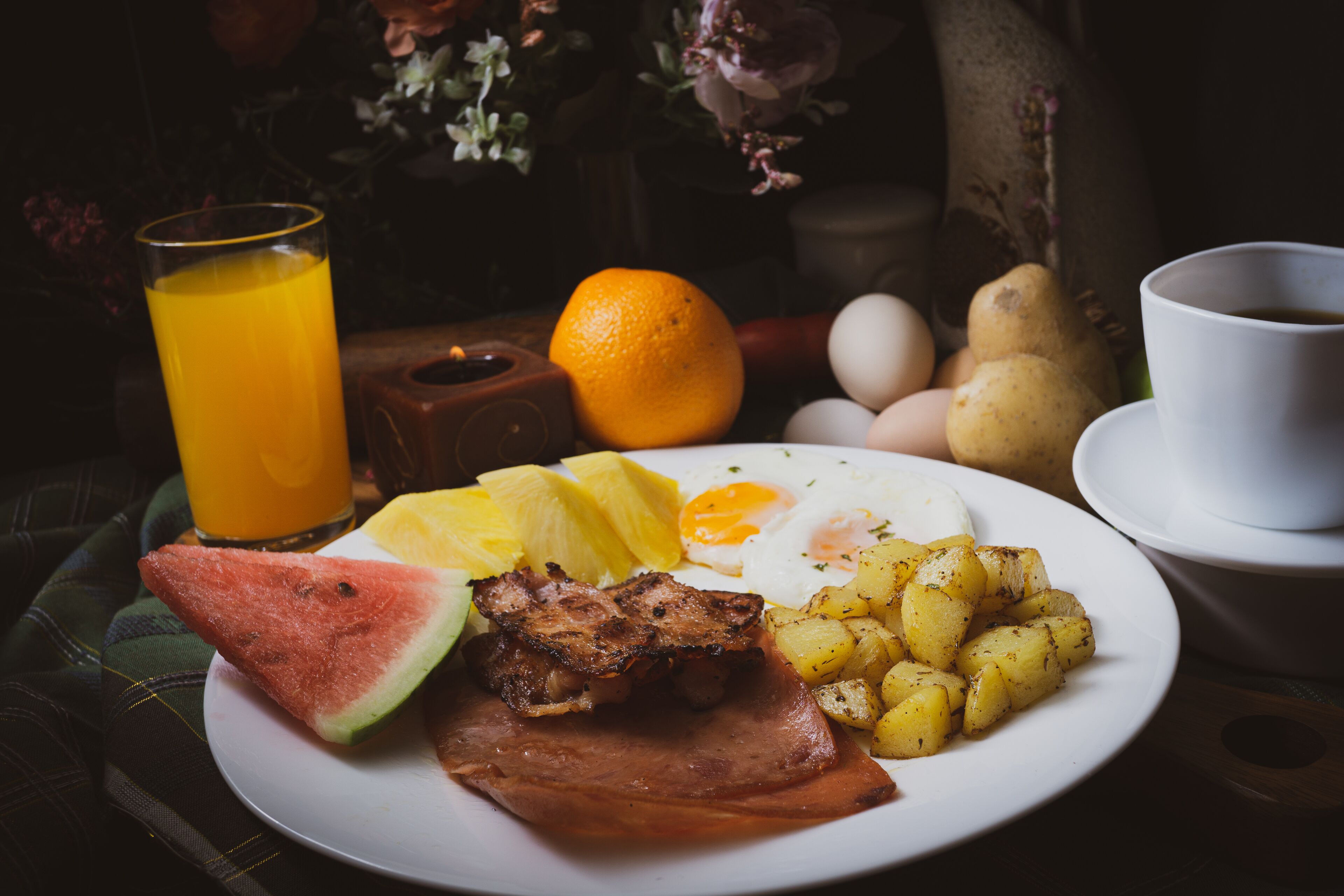 Un plato de desayuno con jamón, huevos, patatas y una tajada de sandía.