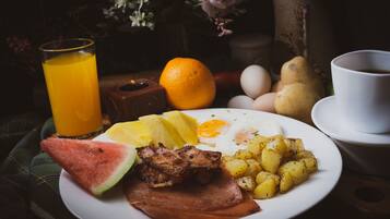 Un plato de desayuno con jamón, huevos, patatas y una tajada de sandía.