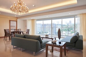 Amplia sala de estar con candelabro, zona de comedor con sillas y mesa, y ventanas grandes con vista a la ciudad.