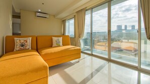 A modern living room with a sofa, a large window with curtains, and a city view. - Alicia Apartelle (Cebu City)