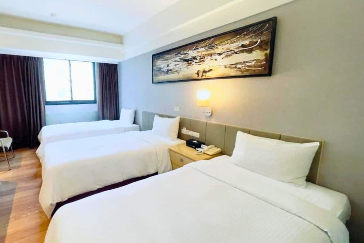 A hotel room with two beds, a desk, a chair, and a painting on the wall.