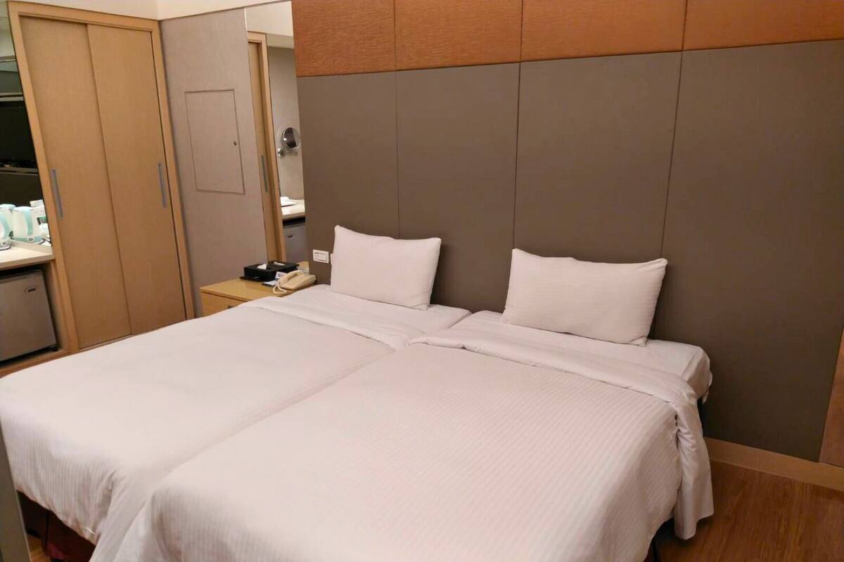 A double bed with white linens in a hotel room.