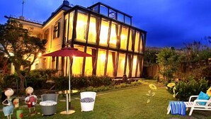A modern house with a glass facade, a red umbrella, and outdoor seating. - Hao Wang Jiao Homestay (Datong)