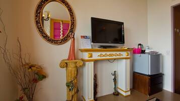 A living room with a TV, a decorative mirror, a statue, and a refrigerator.