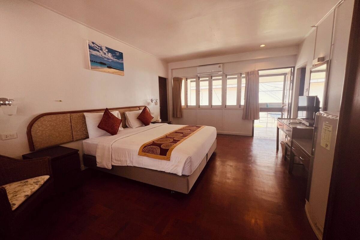 Una camera d'albergo con un letto, un comodino e una scrivania con un computer.