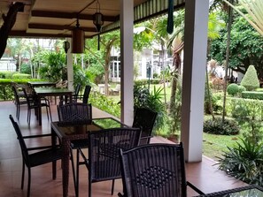 Une terrasse extérieure aménagée avec des meubles en osier et offrant une vue sur un jardin bien entretenu.
