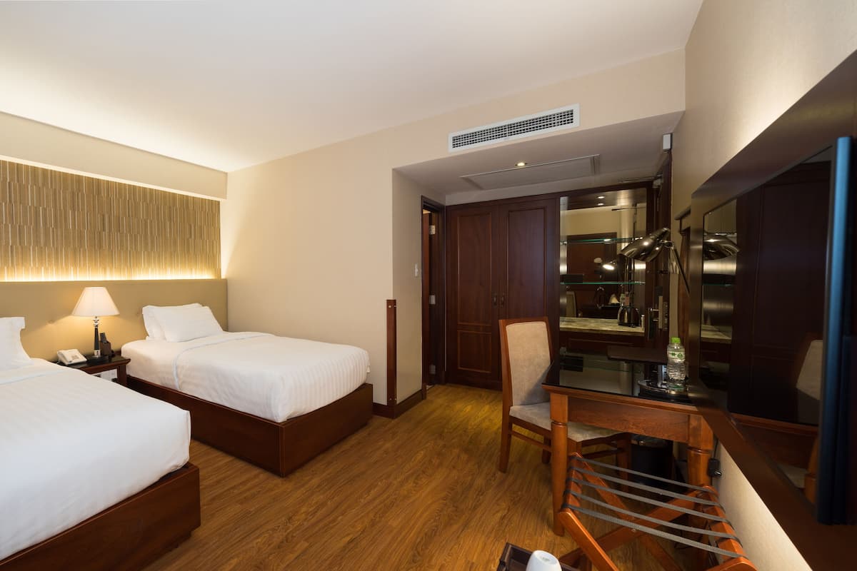 A hotel room with two beds, a desk, a chair, a mirror, and a wardrobe.