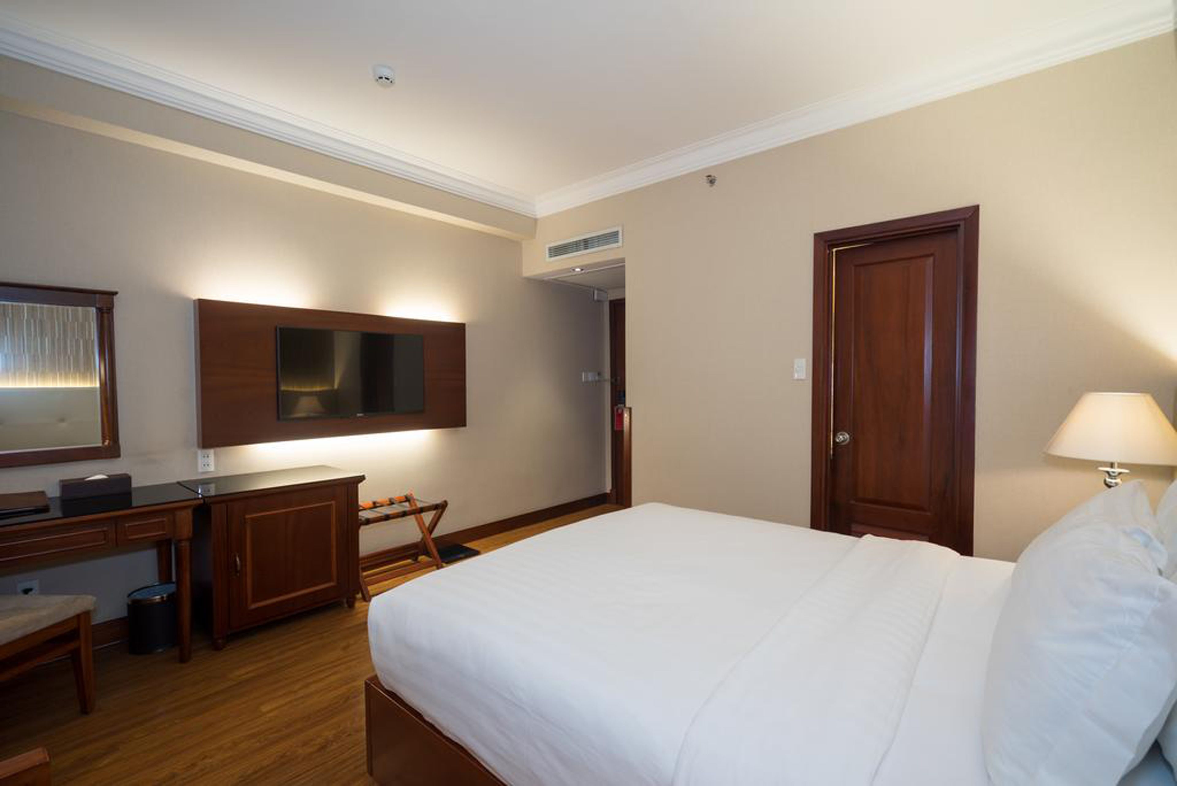 Ein Hotelzimmer mit einem Bett, einem Schreibtisch, einem Stuhl, einem Fernseher und einer Tür.