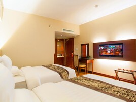 A hotel room with two beds, a desk, a television, and a bathroom visible through an open door.