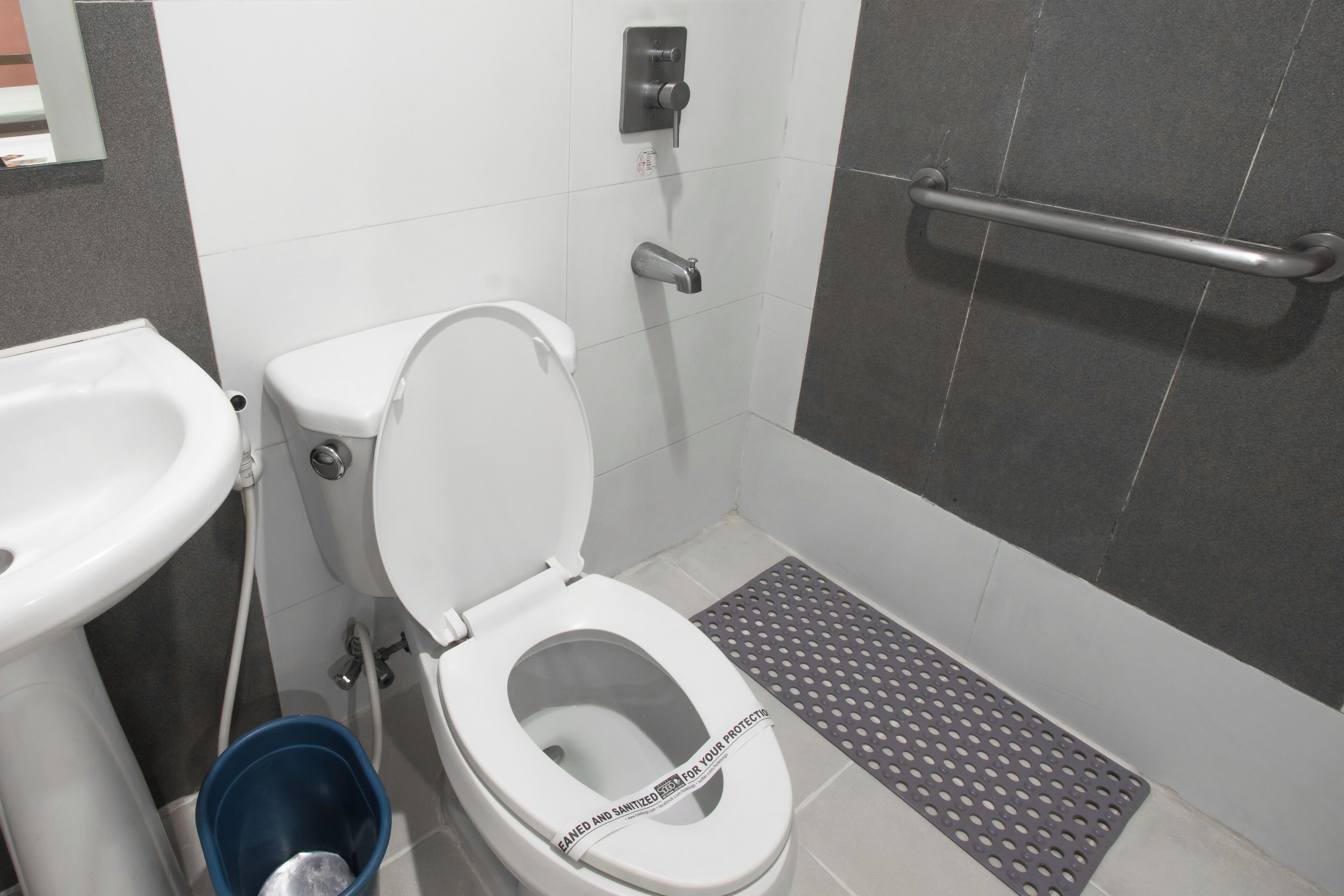 A modern bathroom with a toilet, bidet, and a handrail.