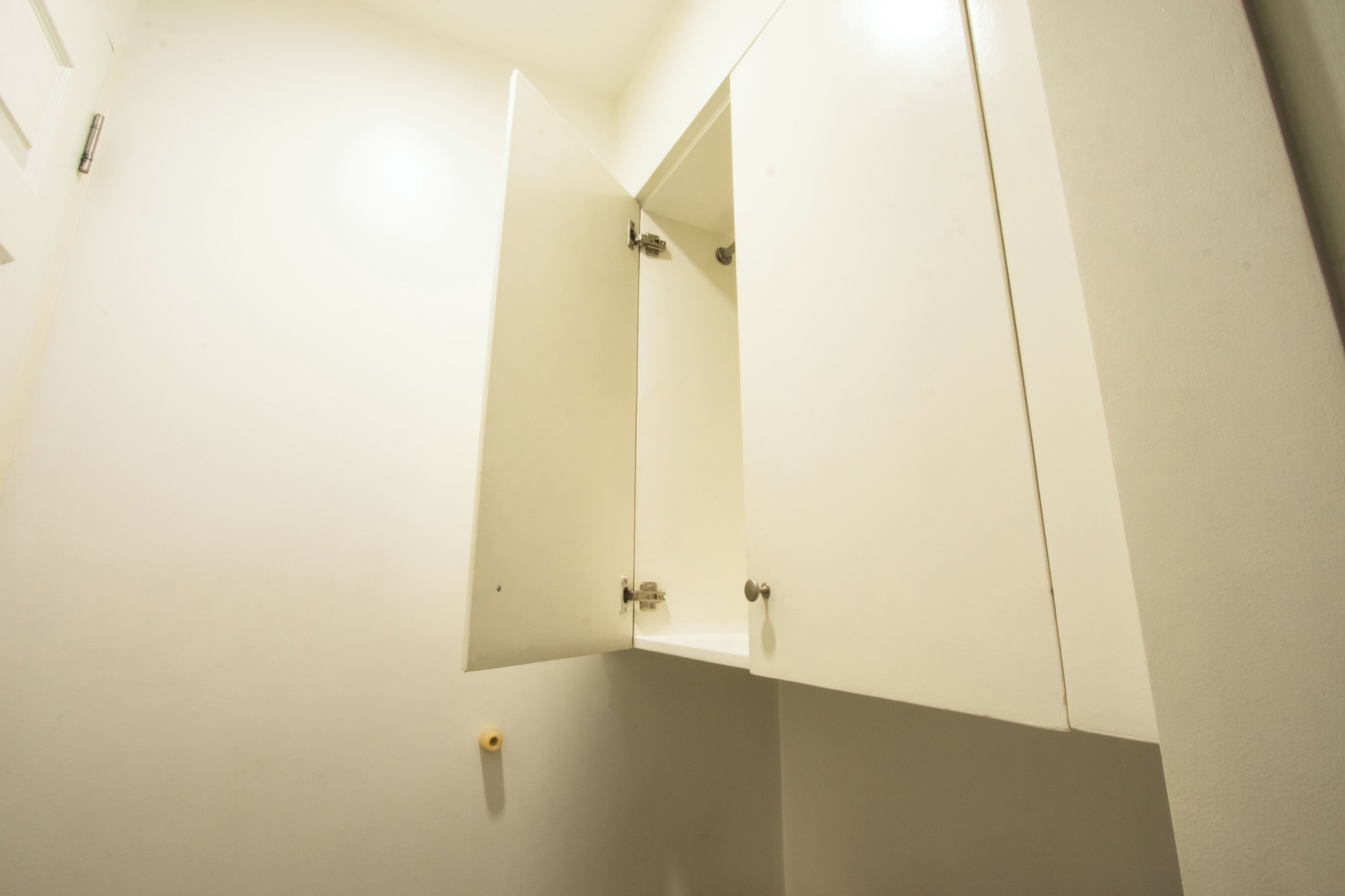 A bathroom with white walls, a mirror, and a door.