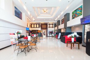 A modern hotel lobby with a reception desk, seating area, and artwork on the walls. - Hotel Sogo Santolan (Pasig)