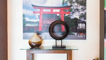 A framed painting of a red torii gate, a vase, and a mirror on a glass table.