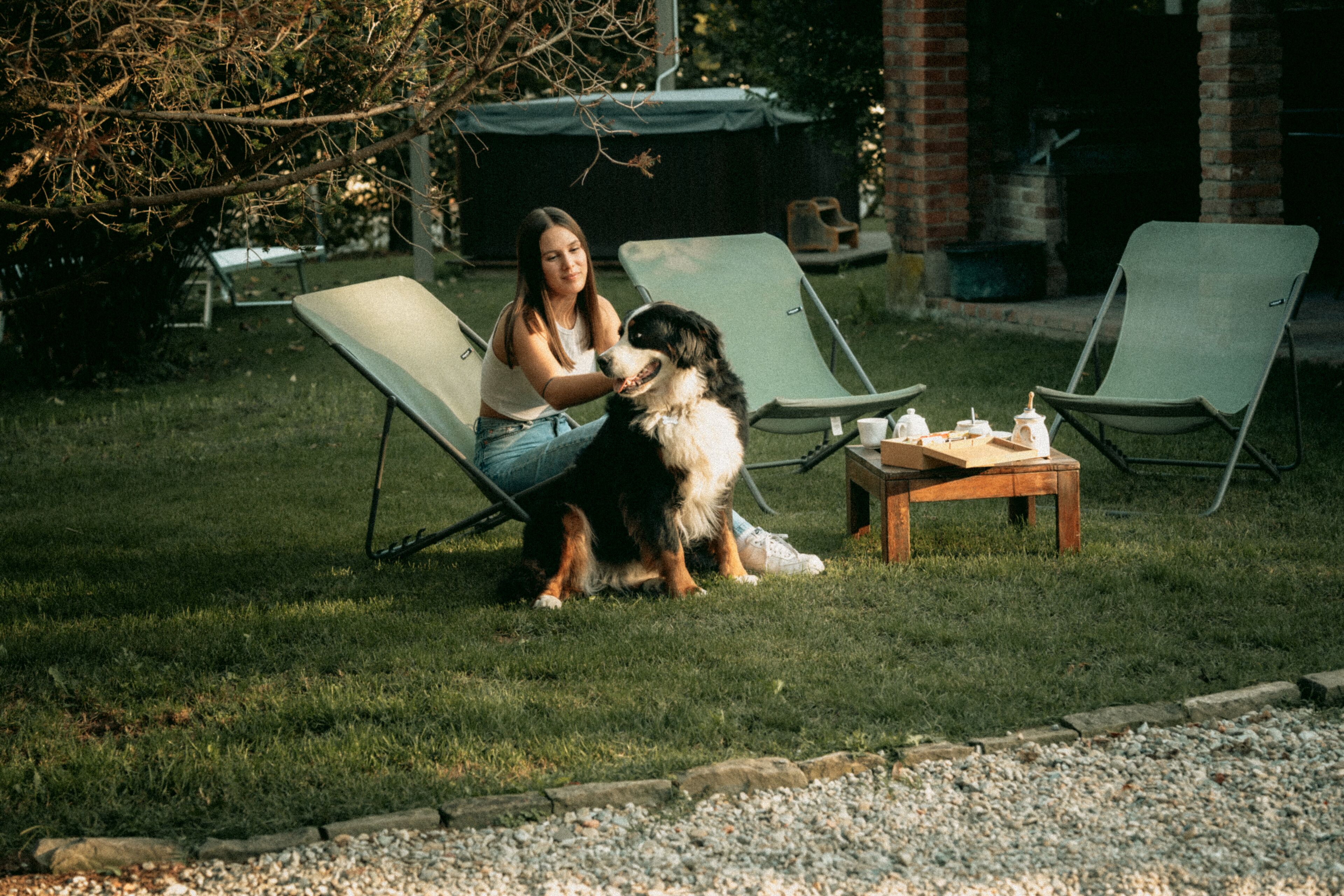 Un espacio al aire libre con césped, dos sillones y una pequeña mesa.