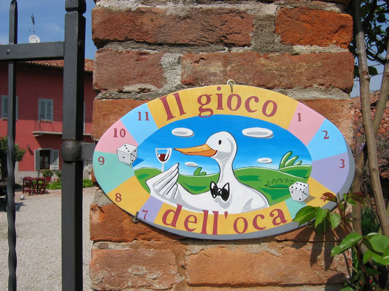 A colorful sign with a duck and the text "Il gioco dell'oca" on a brick wall.