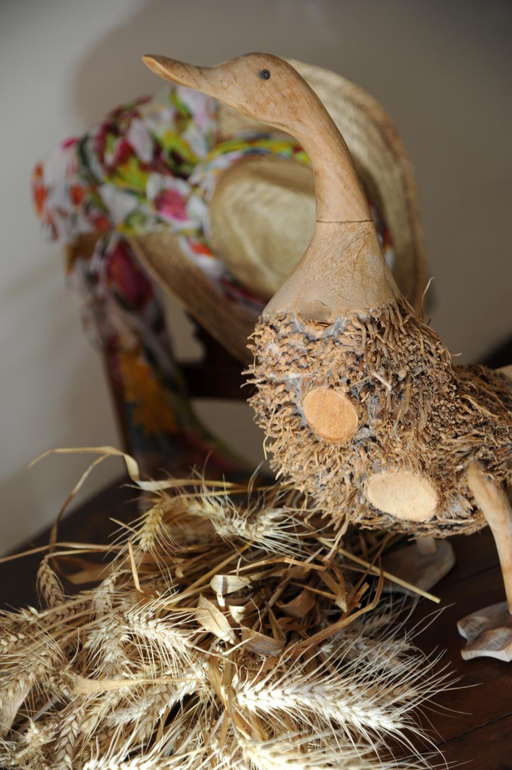 Eine Holzskulptur eines Vogels mit einem Nest aus Stroh und Zweigen.