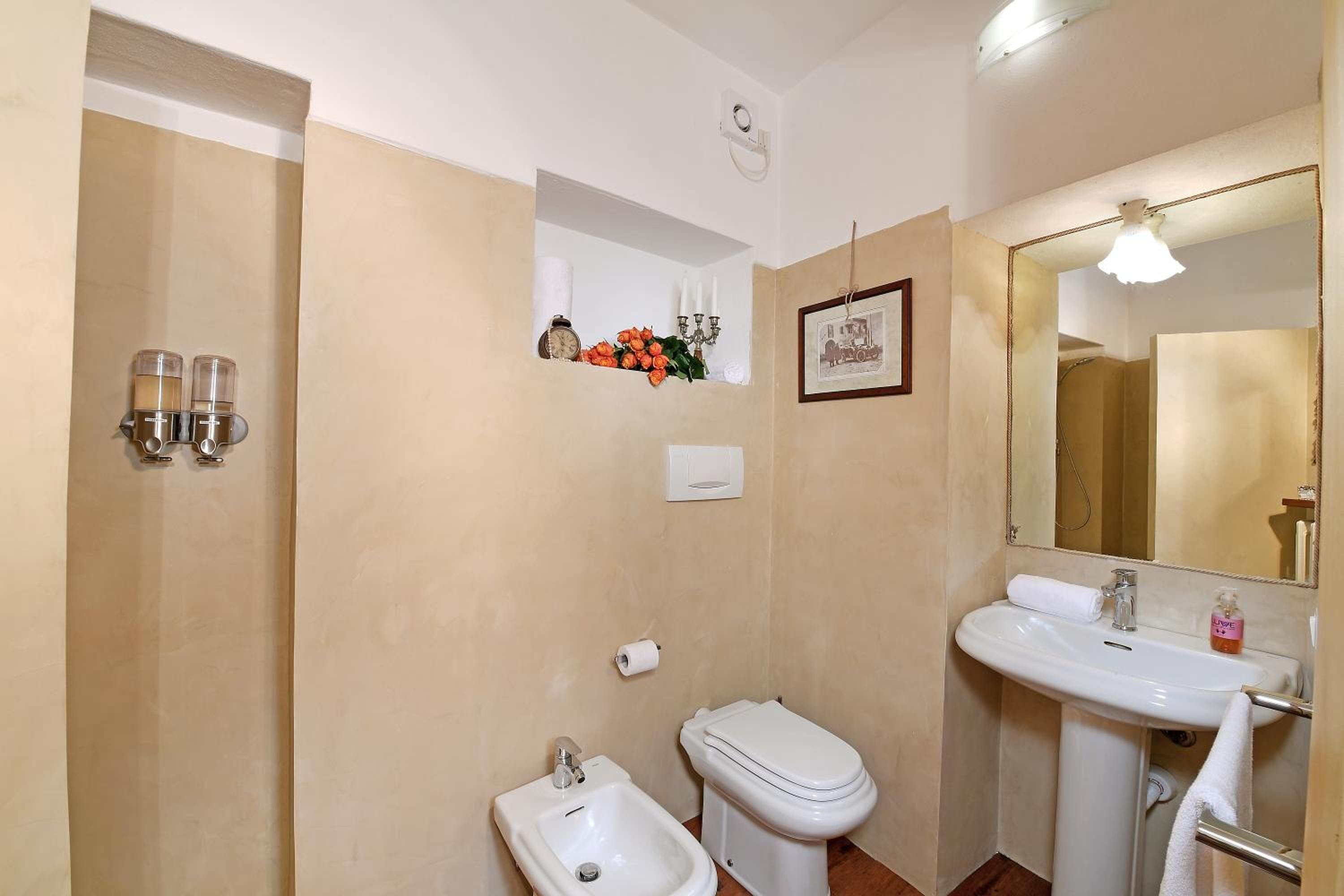 A bathroom with a bidet, toilet, sink, and mirror.