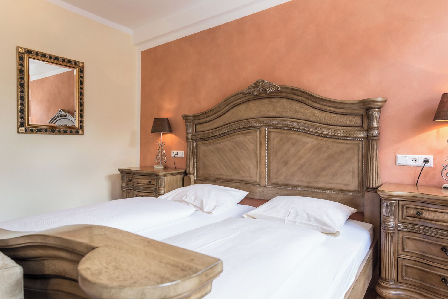 Un lit double avec une tête de lit en bois, deux tables de chevet, une commode, un miroir et une lampe.