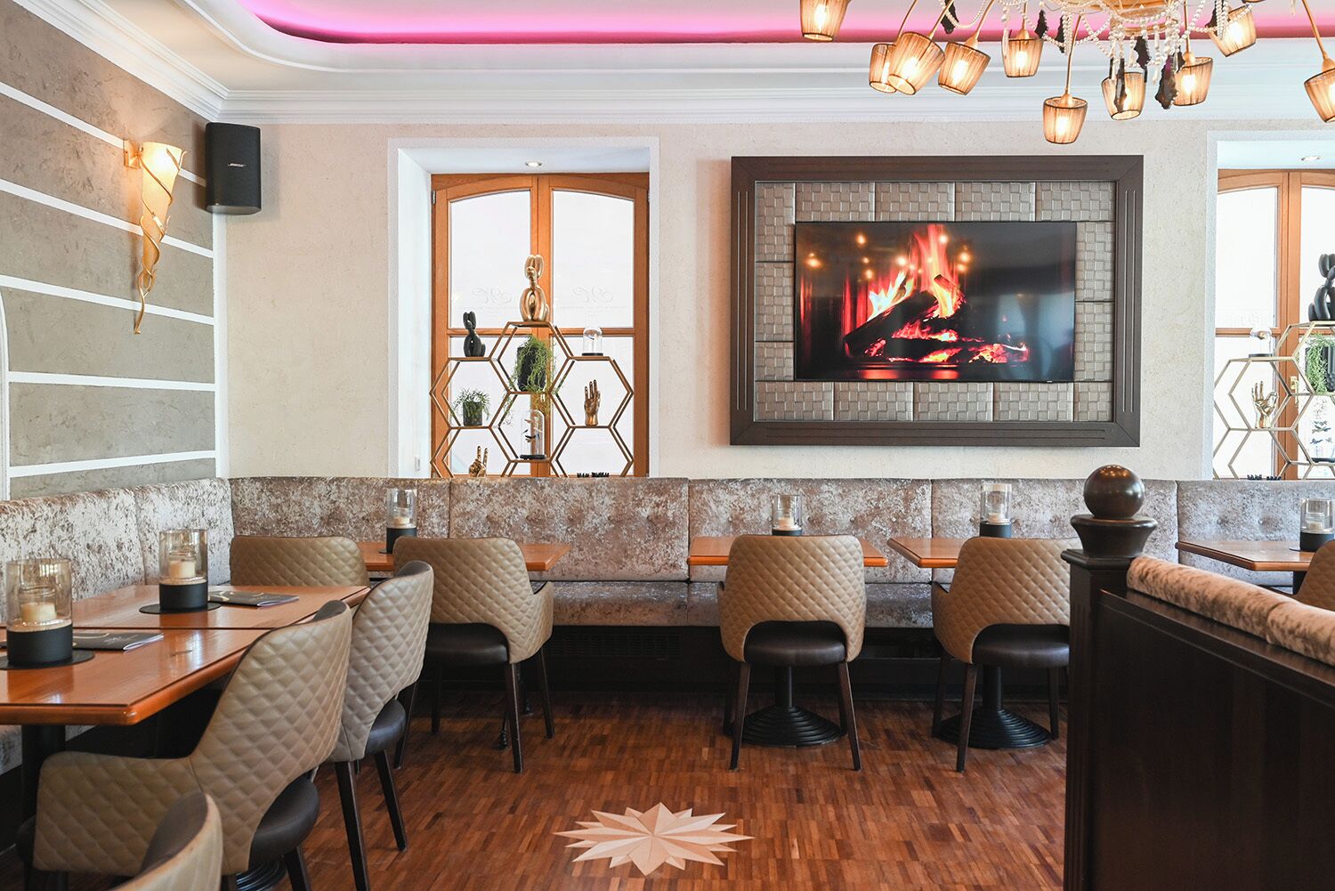 En restaurang med träbord och stolar, en öppen spis med en tv och en dekorativ vägg.