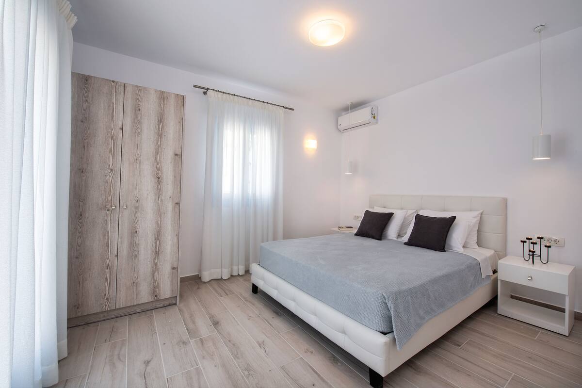 A bedroom with a bed, nightstand, and wardrobe.